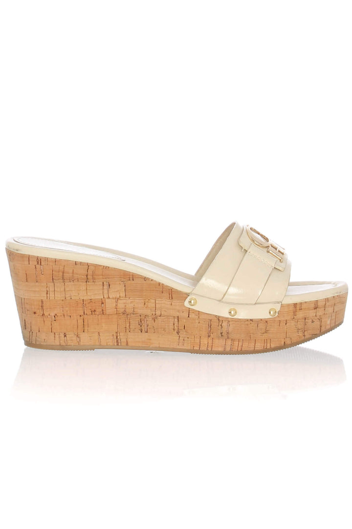 Sandalia mule Coach crema con cuña de corcho y logotipo dorado, vista lateral