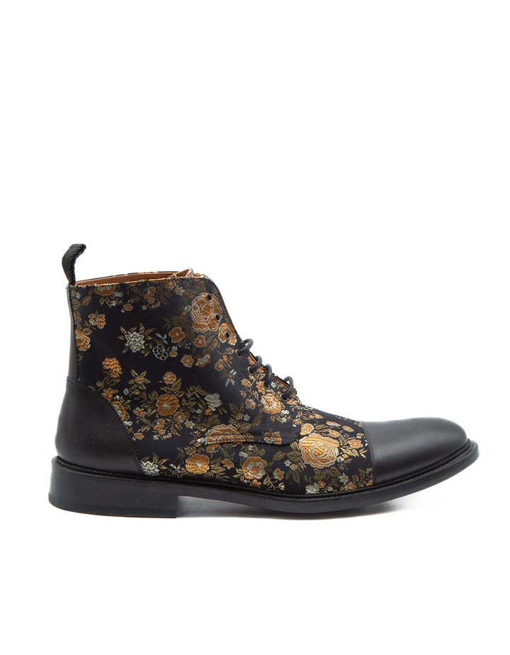 Vista lateral de bota Taft en jacquard floral negro y dorado con puntera de piel