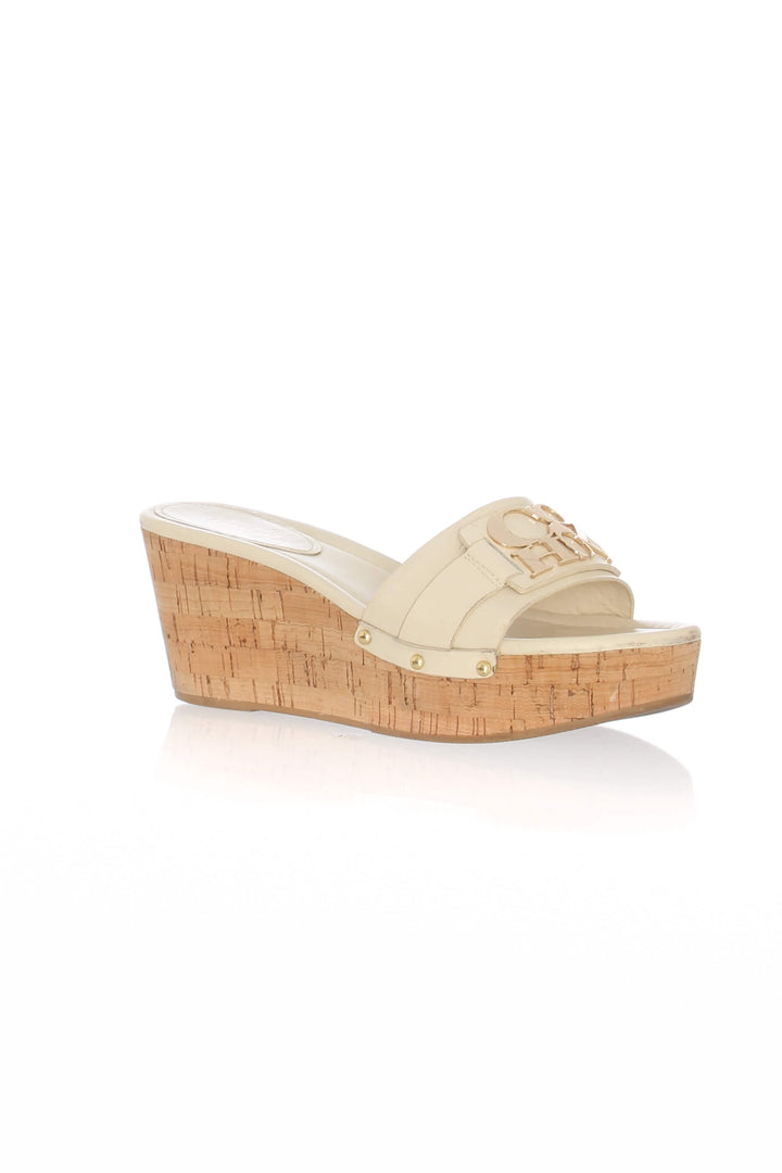 Sandalia mule Coach crema con cuña de corcho y logotipo dorado, vista tres cuartos