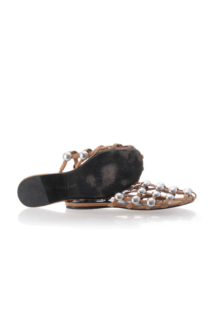 Mules planas Alexander Wang de piel trenzada café con estoperoles plateados, par mostrando suela