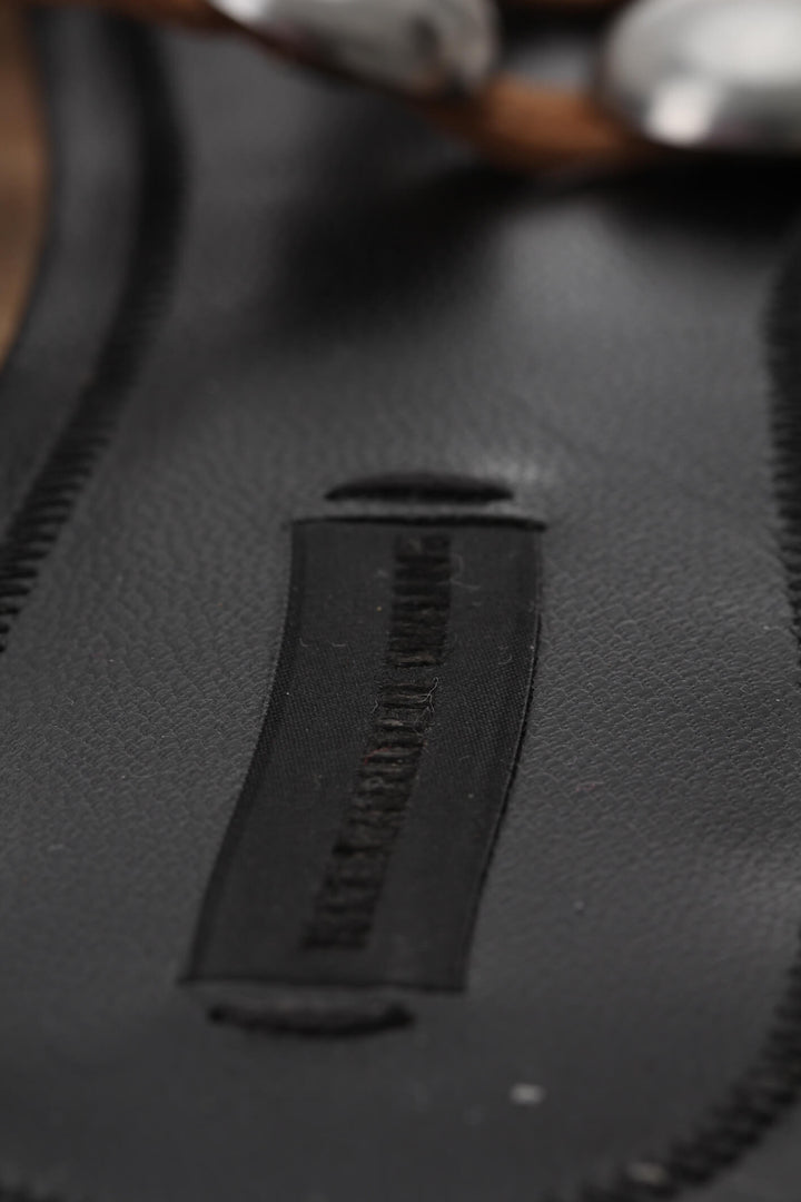 Mules planas Alexander Wang de piel trenzada café con estoperoles plateados, detalle de plantilla con logotipo