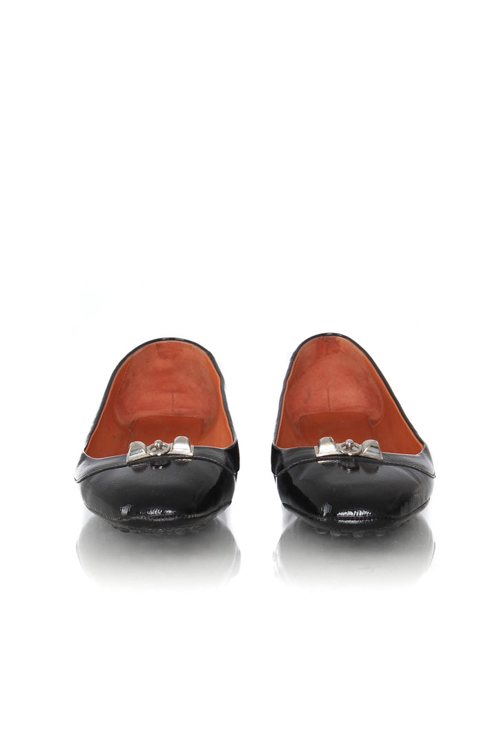 Mocasines Hermès de charol negro con herraje plateado, vista frontal del par