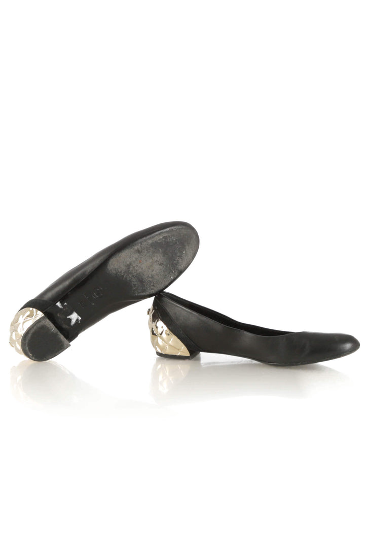 Flats Chanel de piel negra con tacón metálico dorado acolchado, par de lado mostrando suela