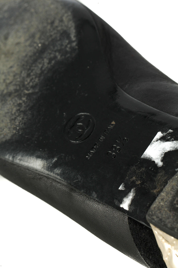 Flats Chanel de piel negra con tacón metálico dorado acolchado, detalle de la suela con logotipo