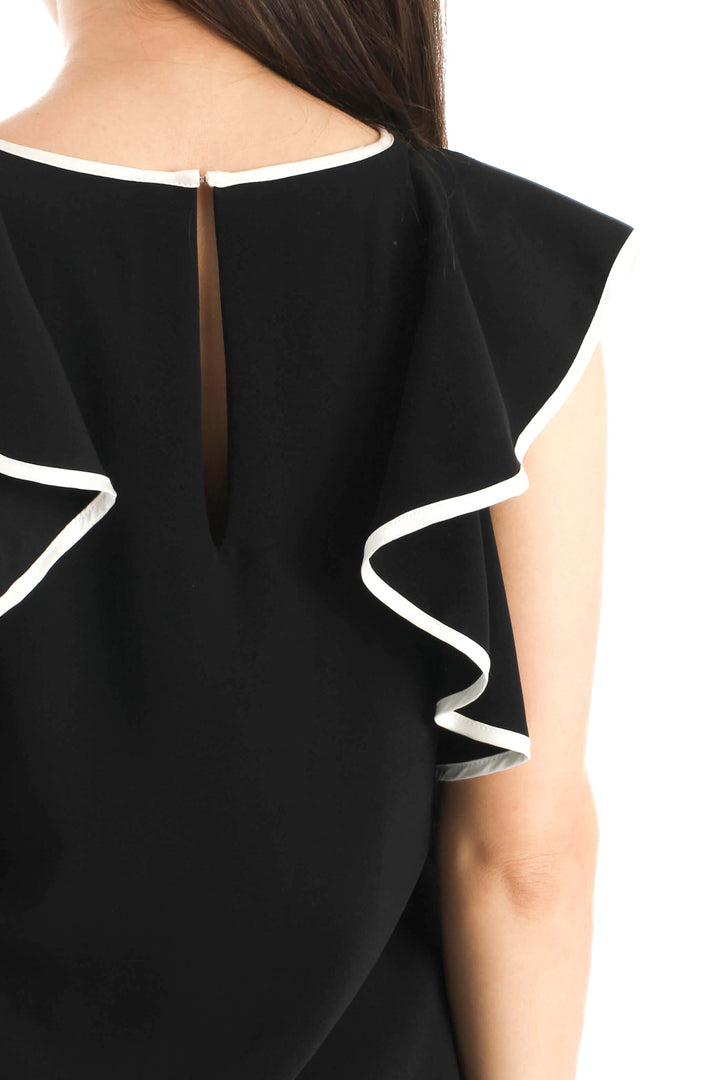 Blusa Amanda Uprichard de seda negra con olanes ribeteados en blanco, detalle de la espalda